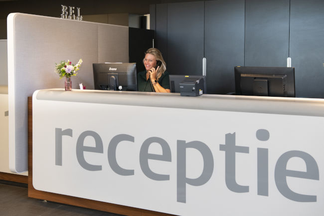 Receptioniste aan de telefoon achter de receptie-balie