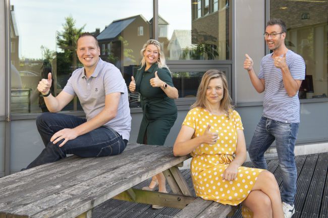Meerdere personen met een blije gezichtsuitdrukking en zij steken hun duim goedkeurend omhoog